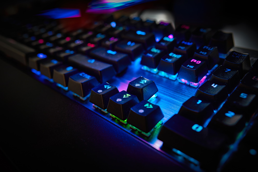 Imagem close-up de um teclado gamer com luzes em LED coloridas nas teclas.