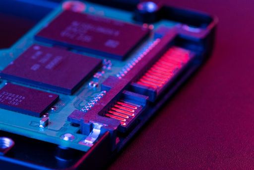Close-up de um circuito eletrônico, mostrando chips e conectores em uma placa. 